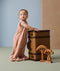 A toddler stands next to a vintage suitcase, wearing a sleep suit bag with a cute elephant print.
