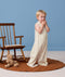 Toddler standing next to a wooden rocking chair wearing an ergoPouch  Sleep Suit Bag 0.2 TOG made from organic cotton.
