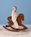 Toddler riding a wooden rocking horse wearing a sleeveless cream printed Sleep Suit Bag.