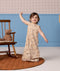 Toddler standing in a beige patterned sleeveless Sleep Suit Bag with one hand raised.