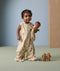 A toddler smiles while wearing a sleep suit bag with a safari animal print, holding a doll that has a matching sleeping bag with the same print.