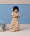 A toddler standing while wearing a tan short-sleeved Sleep Suit Bag in sleeping bag mode.