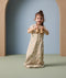 A toddler stands while holding toy binoculars and is wearing a 1.0 TOG sleep suit bag with a safari animal print.