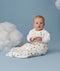 Infant sitting upright against a light blue background with decorative clouds wearing a white Sleep Suit Bag with sleeves