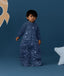 Toddler standing against a deep blue background wearing a Sleep Suit Bag 2.5 TOG Starbeam, featuring long sleeves and star and moon print.