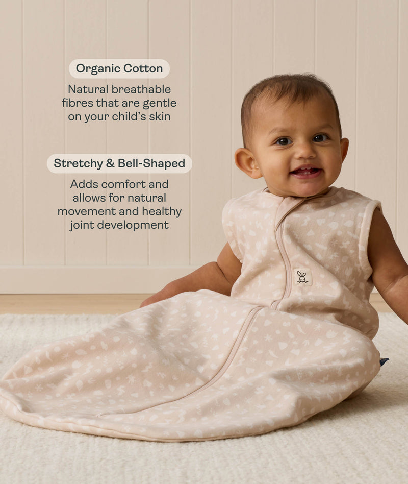 A smiling baby wearing a sleeveless Sleeping Bag 1.0 TOG, sitting upright on a white mat with text highlighting 