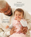 A dad holding a baby wearing a pink, patterned sleeping bag over a long-sleeved layer with text highlighting TOG rating feature and wash & wear care.