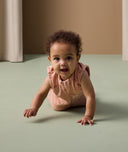 Baby is crawling towards the camera and is wearing a peach-coloured Sleeping Bag with elephant print.