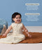 A happy baby sitting on a brown mat wearing a sleeveless, cream sleeping bag with text highlighting 