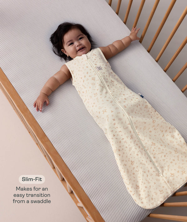 Baby lying in a wooden cot, wearing a sleeveless cream sleeping bag with text highlighting 