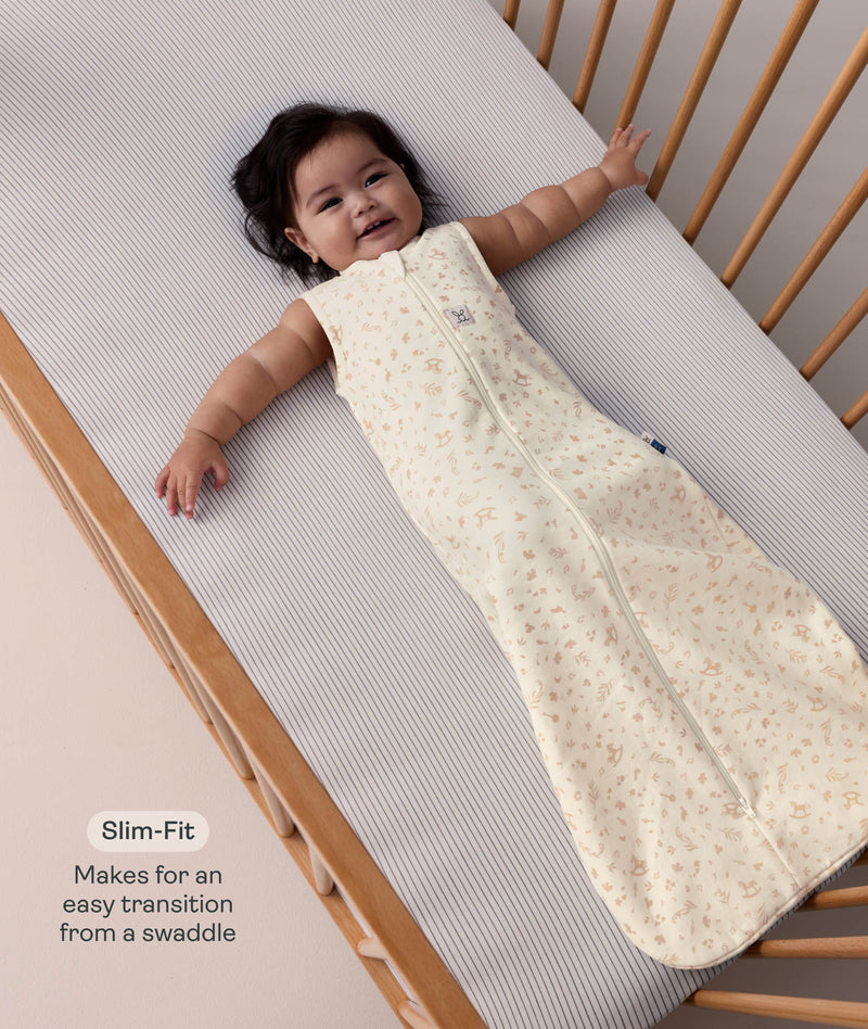 Baby lying in a wooden cot, wearing a sleeveless cream sleeping bag with text highlighting 