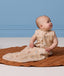 Infant sitting on a brown mat wearing a sleeveless ergoPouch Sleeping Bag 1.0 TOG.