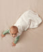 Baby crawling on a plain surface while wearing an oatmeal-coloured sleeping bag over a green long sleeved layer.