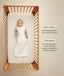 Infant wearing a sleeveless Sleeping Bag lying inside a wooden cot with text highlighting wash & wear and TOG rating features.