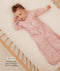 Infant lying in a wooden cot wearing a pink floral sleeved sleeping bag with text highlighting slim fit design for an easy transition from swaddling.