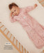 Infant lying in a wooden cot wearing a pink floral sleeved sleeping bag with text highlighting slim fit design for an easy transition from swaddling.