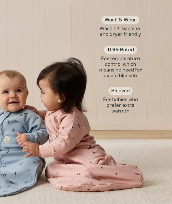 Two babies wearing long-sleeved sleeping bag sit on a carpet. Next to them, text highlights features including 