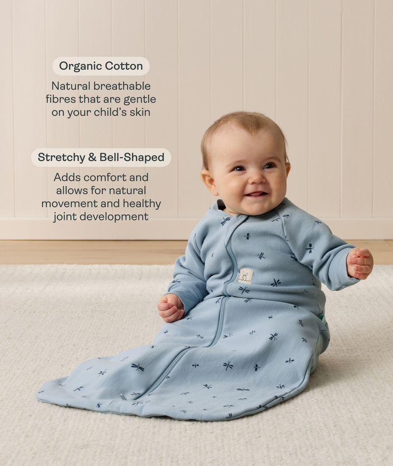Smiling infant wearing a sleeved Sleeping Bag 1.0 TOG Dragonflies with text highlighting organic cotton and stretchy & bell-shaped design.