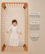 Smiling infant lying in a wooden cot wearing a long-sleeved sleeping bag, with text highlighting wash & wear, TOG rating, and sleeve features.