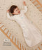 Infant lying in a wooden cot wearing a a long-sleeved Sleeping Bag in Oatmeal Marle with text highlighting slim fit design for easy transition from swaddling.