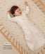 Infant lying in a wooden cot wearing a a long-sleeved Sleeping Bag in Oatmeal Marle with text highlighting slim fit design for easy transition from swaddling.