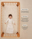 Baby lying in a wooden cot wearing a oatmeal-colored long-sleeve sleeping bag next to product features highlighting Wash & Wear, TOG-Rated, and Sleeved.