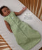 Infant lying in a wooden cot wearing sleeveless Sleeping Bag 1.0 TOG Willow with text highlighting slim-fit design for an easy transition from swaddling.