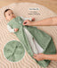 Baby lying on a padded mat while an adult adjusts the zipper of the baby's green sleeveless sleeping bag with text overlay highlighting two-way zip design for easy nappy changing.