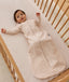 Infant dressed in a long-sleeve patterned Sleeping Bag 1.0 TOG, lying in a wooden cot