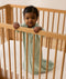 Infant wearing a sage green long-sleeve Sleeping Bag 1.0 TOG, standing inside a wooden cot