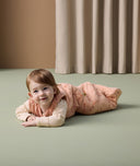 Infant lying flat on its stomach, dressed in an ergoPouch 2.5 TOG Sleeping Bag with a Long Sleeve Layer underneath.