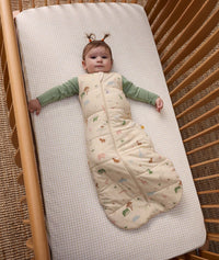Baby lying in a cot, wearing an ergoPouch 2.5 TOG Sleeping Bag with a Long Sleeve Layer underneath.