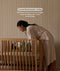 Woman in a robe leaning over a cot with a baby, with text about curved railings.