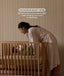 Woman in a robe leaning over a cot with a baby, with text about curved railings.