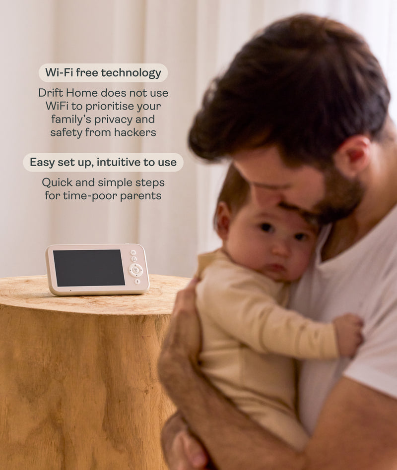 Man holding a baby with the ergoPouch Drift Home Baby Monitor, highlighting the Wi-Fi Free technology and the intuitive nature of the product.