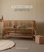 Wooden cot with mattress in a nursery setting, emphasizing safety and adjustability.