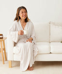 Woman sitting on sofa with a cup of tea, wearing ergoPouch Matchy Matchy Robe in Oatmeal Marle