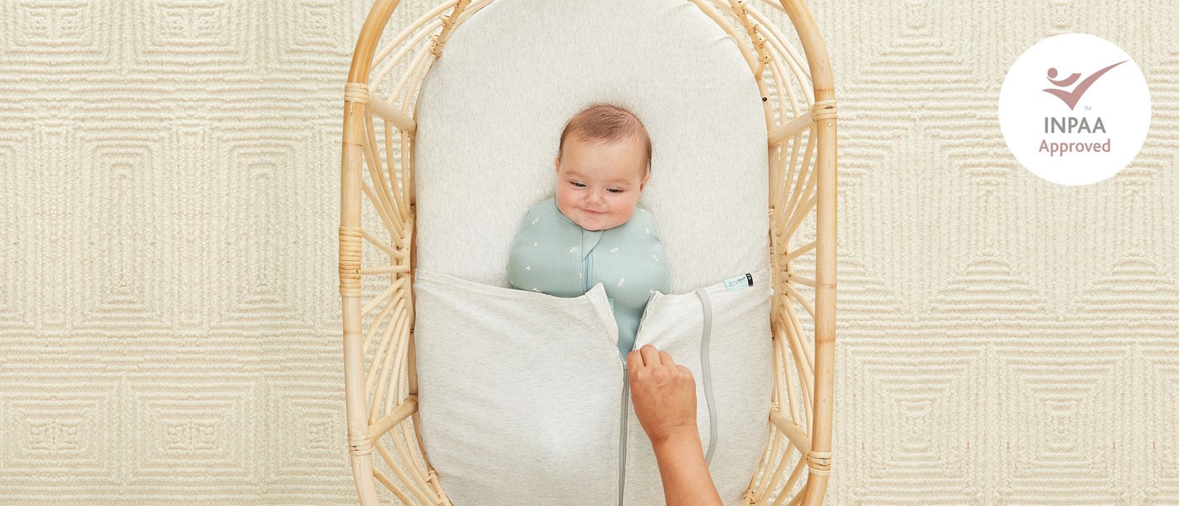 Baby being tucked into bassinet under ergoPouch zip-up Baby Tuck Sheet