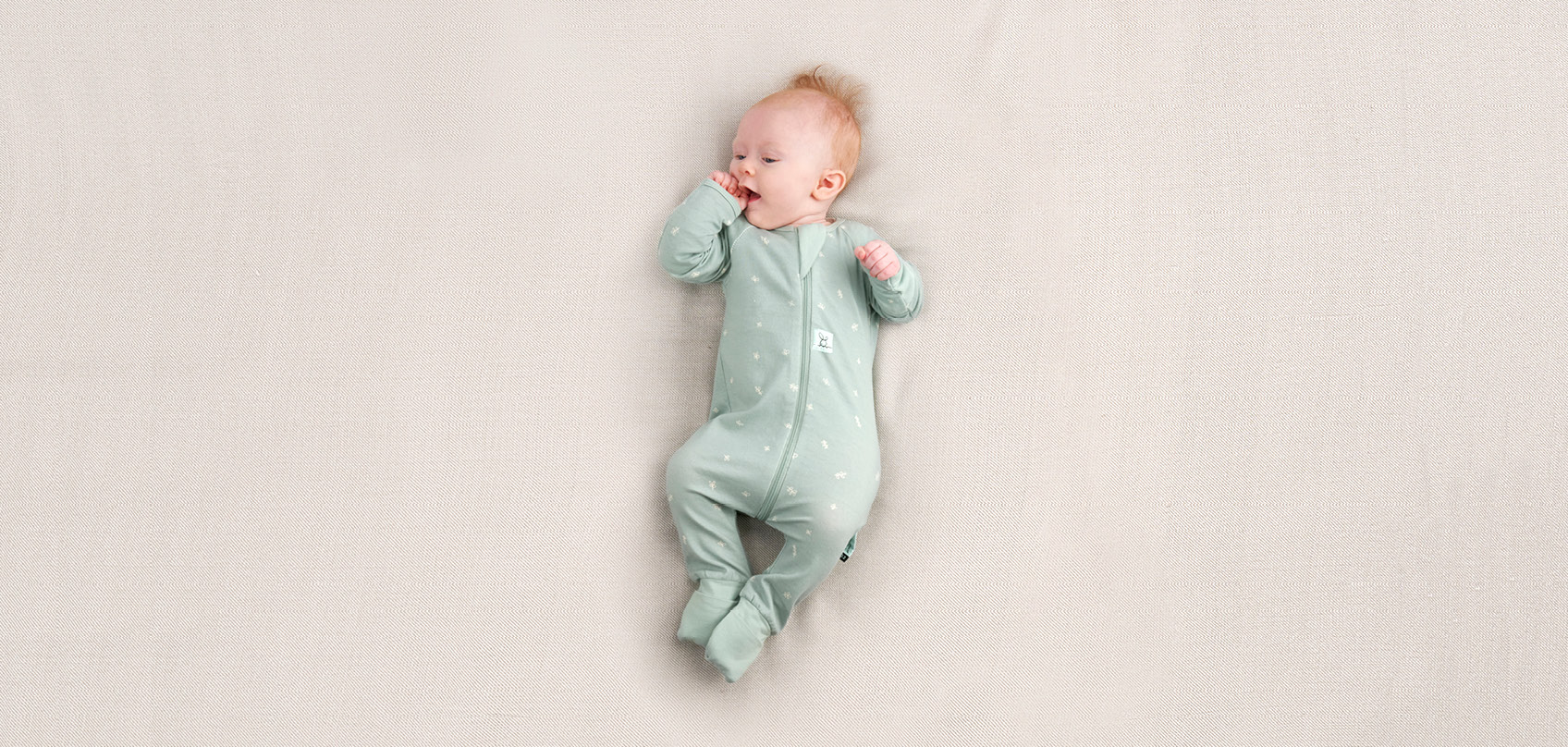 Image of baby wearing a long sleeve baby bodysuit by ergoPouch in the colour Sage