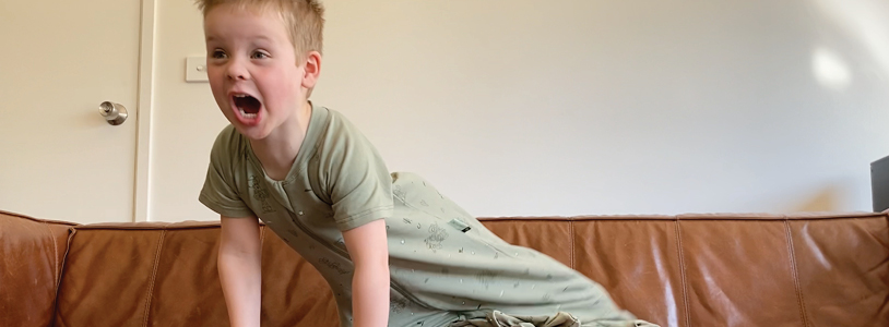 Preschool kid sitting on couch and expressing energy