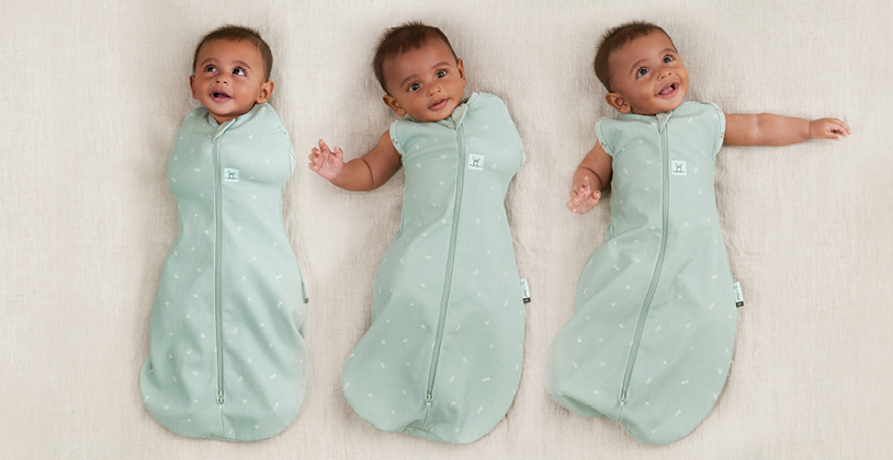 Baby transitioning from arms-in to arms-out sleeping, wearing the ergoPouch Cocoon Swaddle Bag