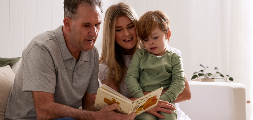 Mother and Grandfather reading a book to toddler
